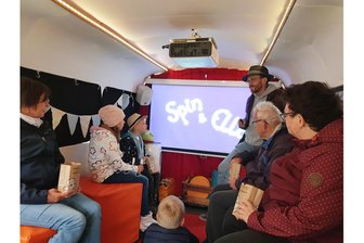 Filmfans rücken im Auerbacher Ortsteil bei Regen zusammen - Im rollenden Kino wird es öfter eng. Hausherr Matthias Ditscherlein erklärt den Ablauf.