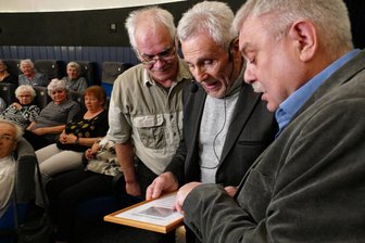 Filmstar am Sternenhimmel verewigt: Gojko Mitic weckt in Drebach großes Staunen - Bei der Übergabe der Urkunde erläutern die beiden Entdecker Gerhard Lehmann (rechts) und André Knöfel (links) Gojko Mitic die genaue Position des Kleinplaneten.