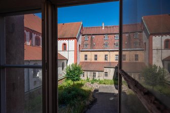 Finanz-Not und Bürokratie-Elend: Wie die Zukunft von Schloss Wechselburg vertan wurde - Blick in den Innenhof von Schloss Wechselburg: Im Fenster spiegelt sich die prächtige Klosterkirche. Doch der Schlossflügel direkt daneben steht leer – und verfällt.
