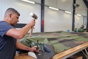 Firma aus dem Vogtland fertigt Fahrzeugplanen für die Bundeswehr: „Aber Waffen würde ich keine liefern“ - Ein Mitarbeiter der Firma Paulus Textil stanzt Öffnungen in das PVC-beschichtete Gewebe. Das Textil in Flecktarn-Optik wird zur Plane für Bundeswehrfahrzeuge. Die Fahrgestelle werden bei Saxas in Werdau gefertigt.
