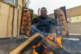 Flammender Genuss mit Glögg lockt auf dem Auerbacher Weihnachtsmarkt - Lukas Lenk hat auf dem Auerbacher Weihnachtsmarkt das Feuer ordentlich angeschürt, damit der Flammlachs gut gelingt.