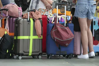 Flugbegleiterin verrät: Das machen die meisten Passagiere im Flieger falsch - Flugreisende mit Kindern warten mit ihren Koffern am Check-In im Flughafen Leipzig-Halle. Wohin gehört das kleine Handgepäck? Die meisten beantworten diese Frage falsch. (Archiv)