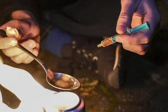 Frankenberg: Woher stammt das Fentanyl bei der Drogentoten? - Eine Person kocht weißes Pulver in einem Löffel über Feuer auf. In der anderen Hand hält sie eine Spritze. Fentanyl ist seit 2018 in der Region im Umlauf.