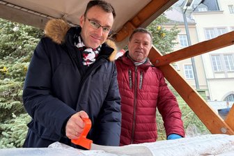Frankenberger Weihnachtsmarkt: Riesenstollen ist angeschnitten - Zur Eröffnung des Frankenberger Weihnachtsmarktes hat Bürgermeister Oliver Gerstner (l.) den traditionellen Riesenstollen angeschnitten. Dabei assistierte ihm Jörg Weiser von der Kulturgesellschaft, die den Markt organisiert und veranstaltet.