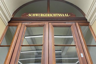Frau soll versucht haben, ihren Vater in Plauen zu töten: Anklage bricht zusammen, Prozess geht trotzdem weiter - Zugang zum Schwurgerichtssaal am Landgericht Zwickau: Hinter dieser Tür muss sich eine 49-jährige Frau verantworten. Sie soll laut Staatsanwaltschaft versucht haben, ihren Vater zu töten.