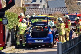 Frau versucht, ihr rollendes Auto zu stoppen und wird in Limbach-Oberfrohna eingeklemmt - Mehrere Einsatzkräfte befreien eine Frau, die eingeklemmt wurde.
