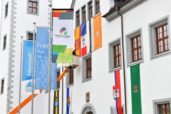 Freiberg legt Festschmuck an: Fahnen der Partnerstädte zieren Rathausgiebel - Die Fahnen von Freibergs Partnerstädten wehen als Festschmuck für das bald beginnende Bergstadtfest am Rathaus.