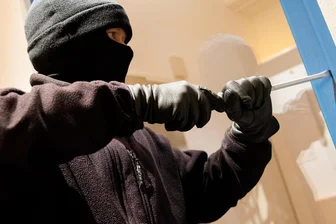 Freiberg: Unbekannte reißen Tresor aus Verankerung - Symbolbild: Ein als Einbrecher verkleideter Mann hebelt ein Fenster auf.