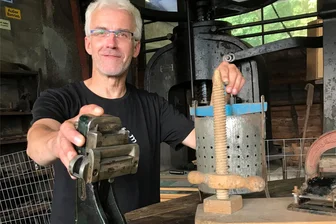 Friedrich-August-Schmiede in Großschirma feiert Pressen-Jubiläum - Tim Meyer mit einer Fahrkartenstempelpresse (links). Im Hintergrund die 160-Tonnen-Spindelpresse.