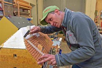 Frischer Schwung für Miniaturschau Klein-Erzgebirge in Oederan: 1500 Figuren werden zum Leben erweckt - Saisonstart im Klein-Erzgebirge Oederan: Tobias Rickmann bringt am Modell des Heimatmuseums von Neuhausen Hunderte neue Holzdachschindeln an.