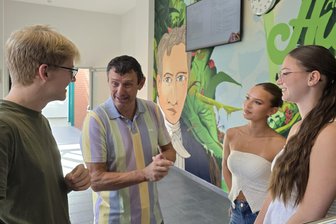 „Früher haben Lehrer und Eltern viel enger zusammengearbeitet“: Werdauer Gymnasium feiert 150-jährige Schulgeschichte - Lehrer Stefan Hoffmann mit den Zwölftklässlern Dominic Seidel, Magdalena Allnoch und Ida Krebs (r.). Das Wandbild im Hintergrund stammt von Graffiti-Künstler Rico Gruner und Schülern.