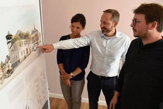 Frühere Post von Bad Elster soll ihren Turm wiederbekommen - Mirjam (links) und Andreas Knopp (Mitte) mit dem Siegerentwurf vom Architektenbüro Frida Architekten aus Dresden. Deren Vertreter Tobias Mausch (rechts) stellte das Konzept jetzt vor.