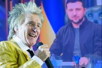 „Fuck Putin“: Rod Stewart singt in Leipzig vor Ukraine-Flagge und wird ausgebuht - Bei seinem Auftritt in Leipzig salutierte Rod Steward (rechts unten, blau-gelb gekleidet) vor dem Bild von Ukraine-Präsident Wolodymyr Selenskyj. Die Reaktion darauf aus dem Liepziger Publikum kam prompt.