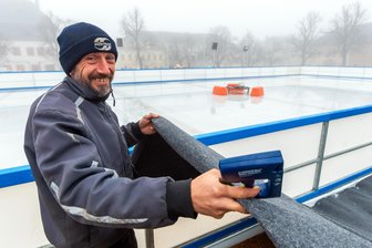 Fünf ultimative Tipps: Das geht am Wochenende im Erzgebirge - Eisarena-Mitarbeiter Sebastian Hähnel legt ein Podest an der Eisbahn mit Filz aus. Währenddessen baut sich bei einer Kühlmitteltemperatur von minus zehn Grad Celsius die Eisfläche auf. Am Samstag geht es los.