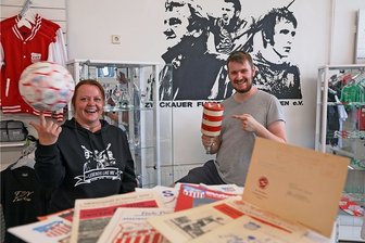 Fußball-Andenken zwischen VEB und Planwirtschaft - Kathrin Maneke und Chris Scheundel beim Aufbau der Ausstellung im FSV-Fanshop. Der Vereinsvorsitzende zeigt die Rassel von Kurt Mehlhorn.