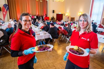 Gänsekeule gratis: Johanniter laden Bedürftige im Erzgebirge zum Adventsessen ein - Carina Schumann (links) und Anna Baar arbeiten in der Verwaltung des Johanniter-Kreisverbandes. Zum Essen für Bedürftige im Auer Kulturhaus brachten sie die Teller mit Gänsekeule, Kloß und Rotkraut zu den Gästen an die Tische.
