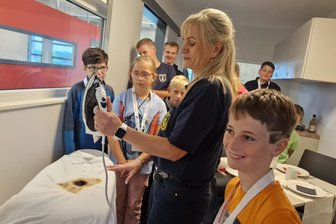 Ganz heiß, ganz hoch, ganz dunkel: So schaut es aus im Brandschutzzentrum Vogtland - Ein heißes Bügeleisen kann der Anfang eines Brandes sein, erklärt Anja Haymann, Pädagogin im Brand- und Katastropehnschutzzentrum. Finn Essbüchel (vorn) hört aufmerksam zu.