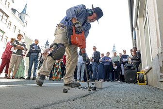Gedenken an NS-Opfer: Lichtensteiner Stolperstein-Verlegung mit kleiner Panne - Stolperstein-Erfinder Gunter Demnig (76) schnitt und bohrte am Freitag ein Loch in den Asphalt vor dem Gebäude Altmarkt 1. Anschließend versenkte er dort Lichtensteins ersten Stolperstein - zur Erinnerung an Hedwig Hammerschlag.