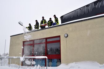 Gefahr durch Schneelast: Kirchberg sperrt Straßen und Wälder - Die Freiwillige Feuerwehr Kirchberg räumt das Dach städtischen Sport- und Mehrzweckhalle frei. 