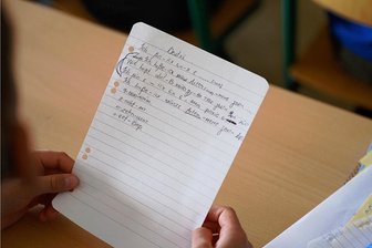 Geflüchtete aus der Ukraine: Zu wenige Lehrer für zu viele Kinder in Auerbach? - Ein Symbolbild: Ein Grundschüler aus der Ukraine hält im Deutschunterricht einen Zettel mit Schreibübungen in der Hand.