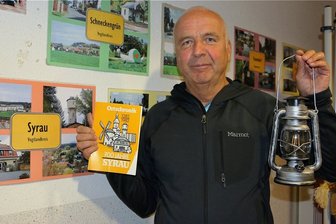 Geht in Syrau das Licht aus? Einwohner lassen Dampf ab - Andreas Scherf hatte als Gast der jüngsten Gemeinderatssitzung eine Ortschronik mit den Syrauer Wahrzeichen auf dem Cover sowie eine Lampe dabei. Ganz nach dem Motto: Der Letzte macht das Licht aus. 