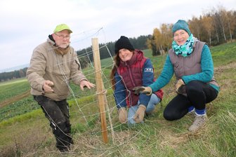Gelände der Stelzenfestspiele bei Reuth bald noch grüner - Peter Staudt, Korina Müller und Anja Süßenguth bringen den Baumschutz aus Draht an.