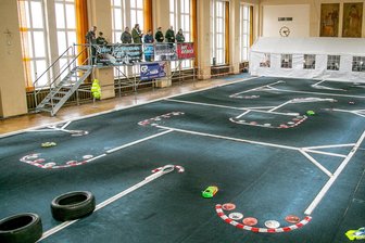 Gelenauer Modellautosportler feiern Dreifachsieg mit schnellen Flitzern - Diejenigen, die während der Läufe ihre Plastikboliden auf Kurs bringen, brauchen eine gute Übersicht über die Rennstrecke. Deshalb stehen sie mit ihren Steuerungseinheiten erhöht, um die gesamte mit Teppich ausgelegte Piste einsehen und die Konkurrenten beobachten zu können.
