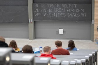 Studierende mit Mund- und Nasenmaske sitzen in einem Hörsaal.