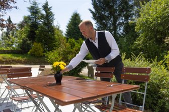 Genussmomente im Erzgebirge: Wo neben Feinschmeckern jetzt auch Wanderer auf ihre Kosten kommen - Servicekraft Ronny Vogel bereitet die neu gestaltete Terrasse für die Gäste vor. Sie bietet noch einmal 40 Plätze. Dort will das Team des Hauses vor allem mit hausgemachten Spezialitäten wie Kuchen und Eis punkten. Serviert wird das neue Imbissangebot ab 1. August.