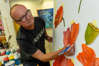 Geschenk für Falkenstein: Wie sich weiße Leinwände in bunte Blumengärten verwandeln - 17 Blumenmotive werden in die Fensternischen der ehemaligen Falgard-Fassade auf der Bahnhofstraße eingesetzt. Bernd Seidel hat sich für Mohnblumen entschieden. Vor dem Malen muss die Bildkomposition stimmen - Seidel probiert.