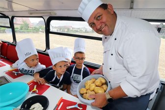 Gesund und nahrhaft: Kinder aus Siebenlehn kochen mit Kartoffeln in großem grünen Bus - Milo, Bennet, Leonidas und Ben schauen interessiert, was Koch Michael Weise (v.l.) vorbereitet hat. Und siehe da: Es sind Kartoffeln.