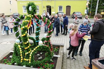 Gornau weiht seinen ersten Osterbrunnen ein - Bei der Einweihung des Osterbrunnens verteilte Bürgermeister Nico Wollnitzke (r.) auch leckere Plätzchen.
