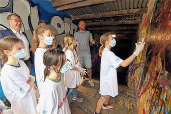Graffiti-Projekt in Freiberg: Kinder und Jugendliche machen aus einer finsteren Unterführung einen Silbertunnel - Oberbürgermeister Sven Krüger (hinten l.) schaut den jungen Künstlern zu. Nico „Cebu“ Roth (M.) gibt noch Tipps.