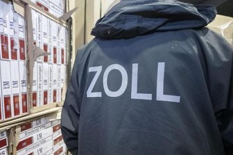 Ein Zollbeamter steht in einer Verwahrstelle des Zolls vor konfiszierten Paletten mit geschmuggelten Zigaretten (Symbolbild).
