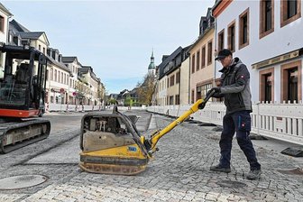Großbaustelle in Innenstadt von Rochlitz: Arbeiten dauern bis Ende November - Ein Mitarbeiter der Rochlitzer HTB verdichtete am Donnerstag mit einer Rüttelplatte das Pflaster am verbreiterten Gehweg. Kommende Woche wandert die Baustelle auf die gegenüberliegende Straßenseite.