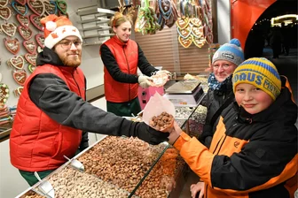 Großer Preisvergleich: Was Bratwurst und Glühwein auf den Weihnachtsmärkten im Erzgebirge kosten - Thaddäus und Peggy Hecht kaufen bei Vanessa Berger und David Wiest (v. r.) auf dem Marienberger Weihnachtsmarkt gebrannte Mandeln.