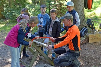 Grünes Klassenzimmer Augustusburg: Wie groß oder klein sind 200 Gramm Holz in der Hand? - Niklas Meier zeigt in Augustusburg die Handhabung der Bogensäge und wie Holzstücke abgesägt werden.