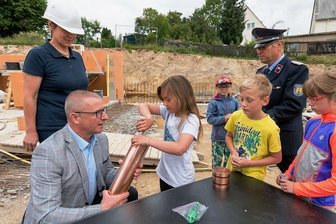 Grundstein für Feuerwehrdepot in Marienberger Ortsteil gelegt - Oberbürgermeister André Heinrich hilft Maida aus der zweiten Klasse der Lauterbacher Grundschule beim Befüllen der Zeitkapsel.