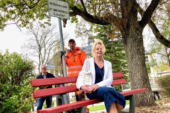 Gute Idee im Erzgebirge gescheitert? Keine Passagiere auf der Mitfahrerbank - In Lauter-Bernsbach wurden 2021 zwei Mitfahrerbänke aufgestellt. In Bernsbach waren Ideengeber Frank Harmsen (hinten links) und Ute Knauft dabei. Bauhofmitarbeiter Kai Leßmüller stellte ein Hinweisschild auf.