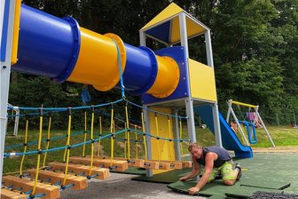 Gute Nachricht: Spielplatz im Muldaer Bad fast fertig - Auf dem neuen Spielplatz im Erlebnisbad Mulda verlegt Marco Reuter, Mitarbeiter im Unternehmen Spiel Spaß Freizeit Klaus Krieh aus Sayda, Fallschutz-Platten.
