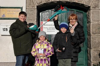 Gute Tat: Frauen aus dem Erzgebirge unterstützen Kinderarche in Markersbach - Hannelore Prager (r.) hat für den Garten der Kinderarche in Markersbach bereits 2021 Obstbäume gestiftet. Nun gab es einen Rasentrimmer, den sie an Philipp, Sophie und Danny übergab.
