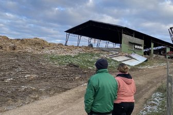 Hallenbrand in Neumark: Eine Familie kämpft um ihren Betrieb und mit Gerüchten - und die Polizei stellt einen Antrag - Fast drei Wochen nach dem Feuer. Winnie und Daniel Seumel vor der ausgebrannten Lagerhalle ihres Neumarker Hofs. Davor die Reste von 800 Heu- und Strohballen, die für die Brandbekämpfung hinausgebracht worden waren.