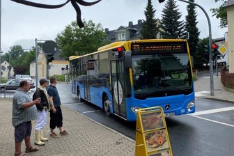 Haltestelle verlegt: Eltern fordern mehr Sicherheit für ihre Kinder - Ein Bus der Linie 53 biegt in die Markersdorfer Straße ein. Wo jetzt der Werbe-Aufsteller steht, gab es bis vor kurzem noch Parkplätze für die Kunden einer Bäckerei und eines Fleischers. Sie klagen nun über Umsatzeinbußen.