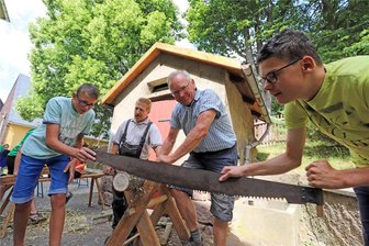 Handwerk, Tradition und Natur: Wie die Grüne Schule grenzenlos in Zethau Wissen und Können vermittelt - Pierre (l.) und Daniel (r.) sägen unter Anleitung von Volker Beer (2.v.r.) und Holger Siefert auf alte Weise.