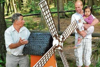 Heimateck "Rentnersruh" lockt mit Sommerfest nach Thalheim - Diese Windmühle ist eines der größten Modelle in der "Rentnersruh". Gebaut wurde sie 1968 von Herbert Preiß. Heinz Hahn (links) stellt sie dem ehemaligen Meinersdorfer Heiko Scholz mit Tochter Vanessa vor.