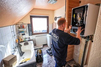 Heizen im Erzgebirge: Kann Wasserstoff eine Rolle spielen? - Ein Mitarbeiter einer Sanitär- und Heizungsbaufirma installiert eine moderne Gasbrennwerttherme in einem Einfamilienhaus. Doch welche Rolle spielt das Erdgasnetz in 20 Jahren?