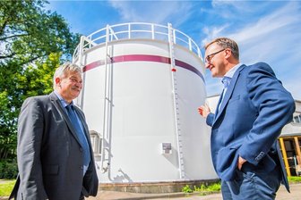 Heizen im Winter: Aue-Bad Schlema bereitet für Zeller Berg Plan B vor - Mit diesem Tank will Aue für Heizsicherheit auf dem Zeller Berg sorgen. René Rücker, der Geschäftsführer der Stadtwerke (r.), erläutert Oberbürgermeister Heinrich Kohl die Möglichkeiten. Die rote Markierung auf der Messlatte kennzeichnet den Füllstand - allerdings indirekt. Zurzeit ist der Tank zu einem Drittel voll.