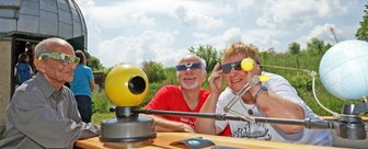 Helle Freude über eine Finsternis - Mit dem Rücken zur Sonne - nur fürs Foto: Die Astronomiefreunde Erhard Liebold (links) sowie Jürgen und Monika Müller haben zur Sonnenfinsternis ein Modell aufgebaut, das das Himmelsereignis verdeutlicht. 
