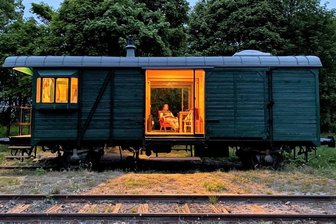 Herberge auf Schienen: Wie Tschechen einen Bahnhof im Erzgebirge retten - Eisenbahn-Glamping im stilvoll umgebauten, 70 Jahre alten Güterwaggon mit Kabine für Zugbegleiter.