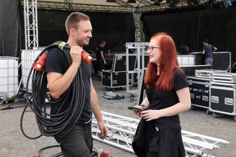 Hier im Erzgebirge steigt am Wochenende das höchstgelegene Festival Deutschlands - Der Aufbau der Bühne am Oberbecken in Makersbach läuft: Helferin Jenny Thomas im Gespräch mit Techniker Max Steudel.